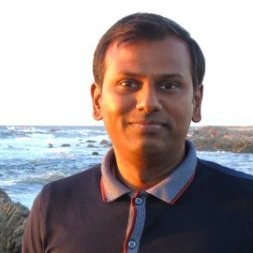 Retrato de Cheenu Venkatachary, um homem indiano usando camisa polo, em uma foto tirada ao sol em frente ao mar